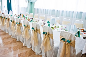 Decorated wedding chairs with golden and green velvet ribbons