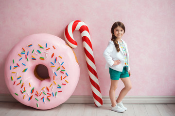 Portrait of a dark-haired girl on a pink background with Christmas candy