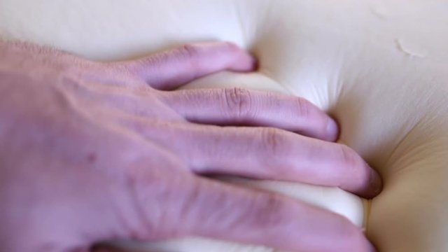 Fingers of a man is Pressing on a Memory Foam White Pillow to test its Softness and Memory.