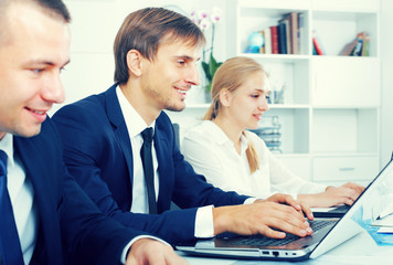 Glad business male sitting with coworkers