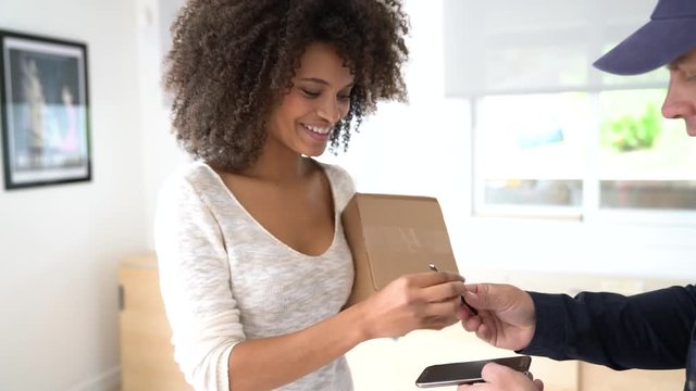 Mixed race woman receiving package from delivery man