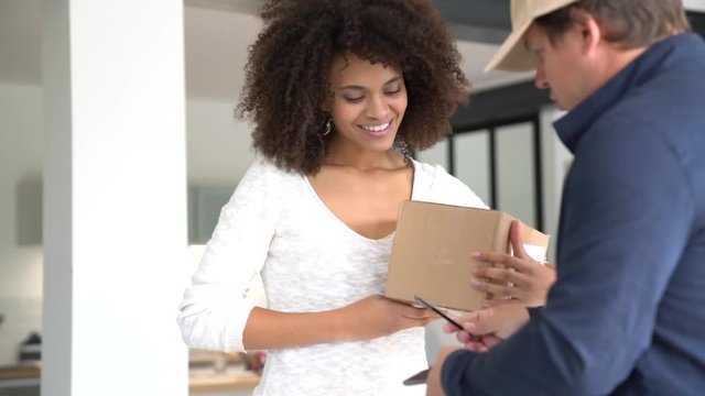 Mixed race woman receiving package from delivery man