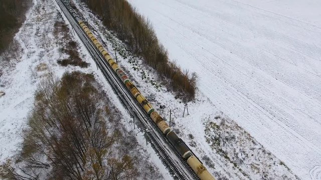 Freight train on the railway in winter. Gasoline, fuel tanks. Aerial shot. 4K.