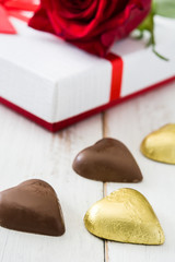 White gift box, roses and chocolate with heart shape on wooden table.copyspace
