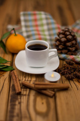Small white cup of coffee, cinnamon sticks, star anise and mandarin on wooden background