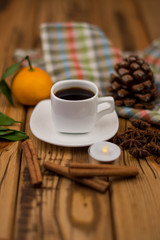 Small white cup of coffee, cinnamon sticks, star anise and mandarin on wooden background