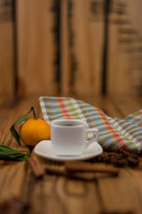Small white cup of coffee, cinnamon sticks, star anise and mandarin on wooden background
