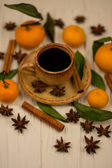 Small white cup of coffee, cinnamon sticks, star anise and mandarin on white wooden background