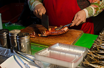 A female hawker cutting broiled cuttlefish in Taiwanese traditional market. Red, green, brown,...