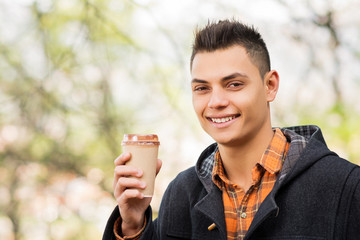 Young handsome man in autumn with cup of takeaway coffee