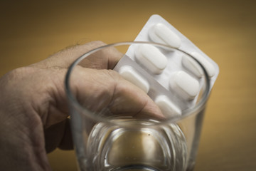 Hand mit Tabletten ung ein Glas Wasser