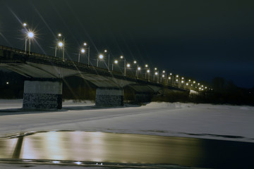 Night lights on the bridge and snow on the river