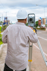 Obraz premium A surveyor at work with an infrared reflector used for distance measurement on roadside A land surveying professional is called a land surveyor.