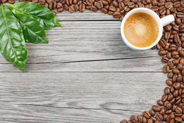 coffee cup, coffee beans and leaves on wooden background