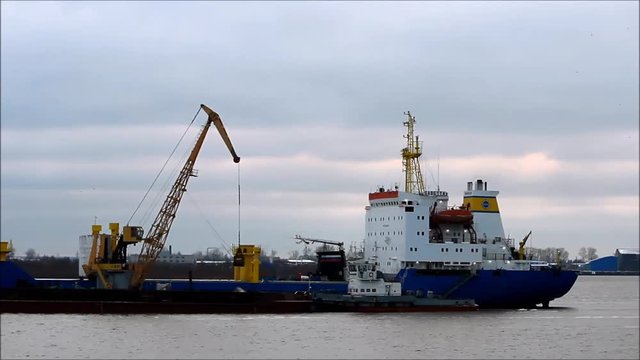 the process of loading coal from the barge to the ship on the river with the help of the port cargo crane.