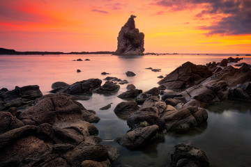 Beautiful seascape sunset scenery of big boulder stone with small rock foreground at Sawarna beach, Banten, Indonesia