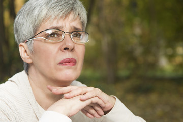 Close up portrait of lovely middle aged woman in the autumn park