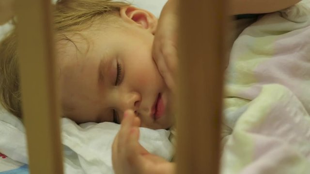 the sweet baby sleeps in a cot and flinches in her sleep