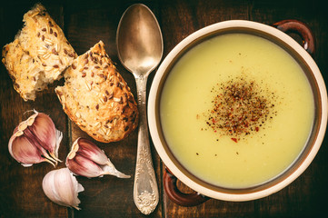 Garlic cream soup with cheese on brown wooden background.