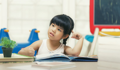 Decent school child. holding her head with a hand and reading a book