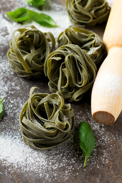 Raw pasta Tagliatelle Paglia e Fieno on a dark background. Selective focus.