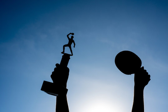 Champion and winning concept for table tenis. Silhouette of a hand holding a championship trophy against the sky