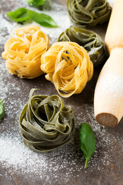 Raw pasta Tagliatelle Paglia e Fieno on a dark background. Selective focus.