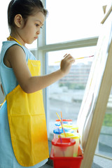 Young girl with apron, painting on easel