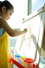 Young girl with apron, painting a rainbow