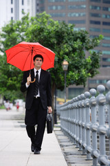 Businessman walking with briefcase and red umbrella