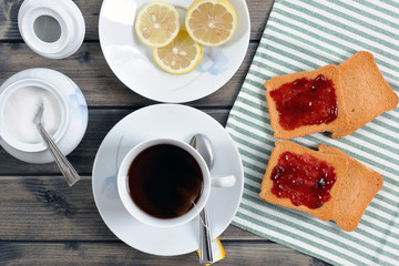 Foods of the Italian breakfast with tea and rusks with jam on an old wooden table, photographed from above