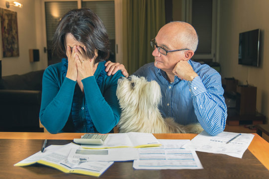Worried couple with dog reading an important notification in a letter sitting in the living room at home