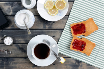 Foods of the Italian breakfast with tea and rusks with jam on an old wooden table, photographed from above