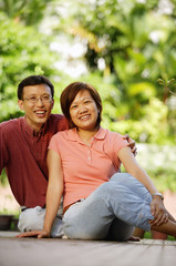 Fototapeta premium Couple sitting on floor, looking at camera