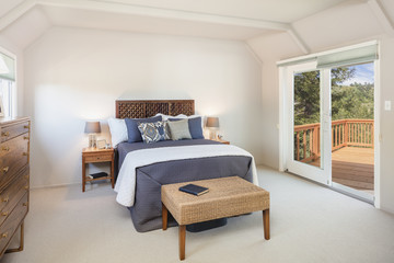 Traditional bedroom with sliding door leading to wooden deck balcony.