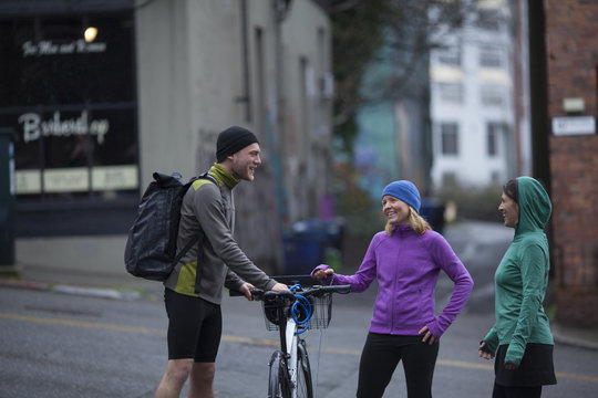 A man with a bike and two women chatting on the side of a Seattle, Washington city street.