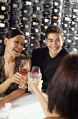 Young adults in restaurant, holding wine glasses, toasting