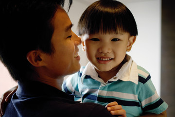 Young boy carried by dad, looking at camera