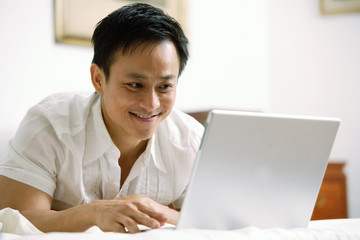 Man in bedroom, using laptop