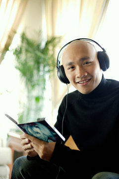 Man in black turtleneck, wearing earphones, looking at camera