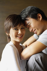 Couple sitting with foreheads touching, woman smiling at camera