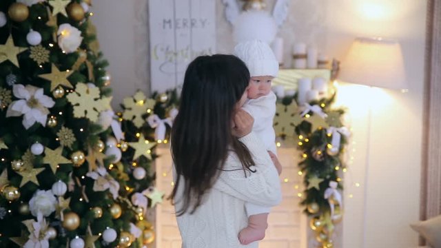 Mother dancing and kissing little son in the christmas studio