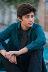 Handsome Latino teen seated while looking to right. 