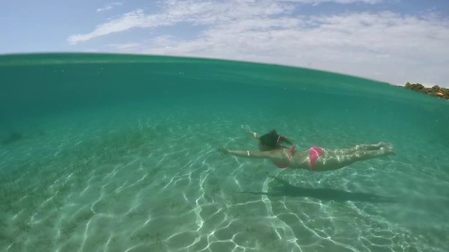UNDERWATER: Lovely girl with long brown hair swimming underwater in ocean