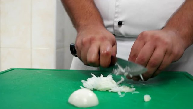 cook cut onion a large kitchen knife, Professional Travel kitchen chef restaurant chef in the form of work, preparing meals for the visitors of the restaurant, fast cutting of veget