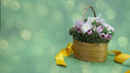 basket with flowers on a green background, yellow satin ribbon