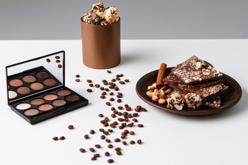Decorative cosmetics coffee beans and chocolate over white background.