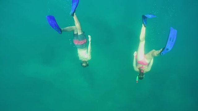 SLOW MOTION UNDERWATER: Two friends snorkeling in beautiful crystal clear ocean