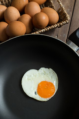 Fried egg on pan and fresh eggs.