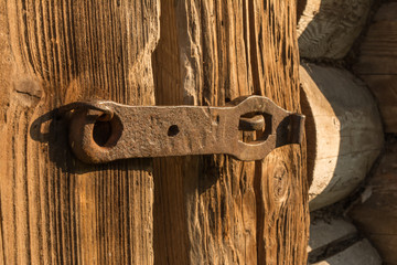 old wooden door closed padlock on the metal on which the sun shines brightly